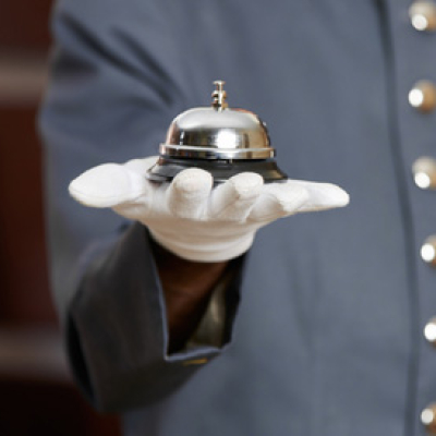 Hotel bell on hand of a hotel clerk at the reception